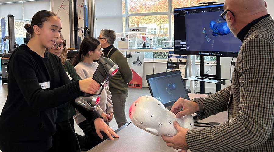 A female student uses a 3d scanner with the help of an AMETEK France team member